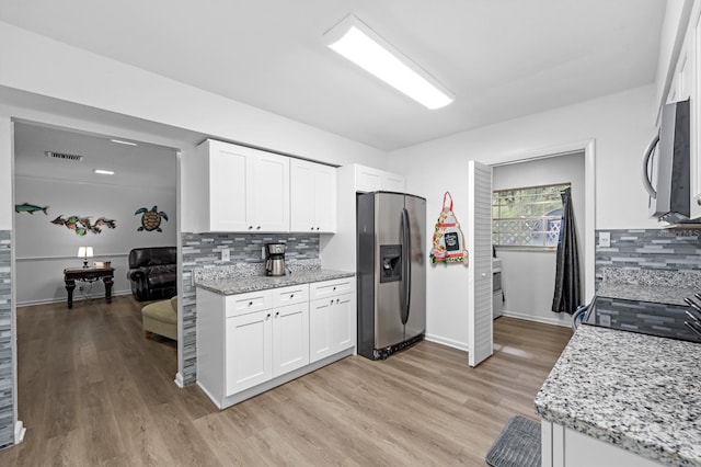 kitchen featuring visible vents, white cabinets, appliances with stainless steel finishes, light stone countertops, and light wood-style floors