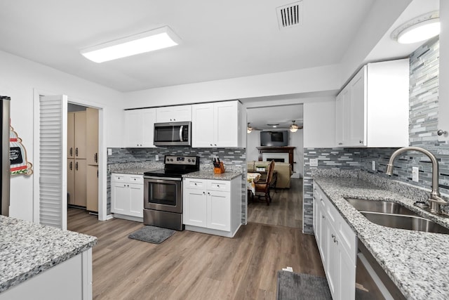 kitchen featuring visible vents, appliances with stainless steel finishes, light wood-style floors, white cabinetry, and a sink