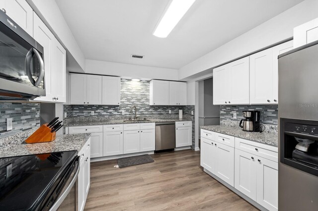 kitchen with light wood-style flooring, a sink, visible vents, white cabinetry, and appliances with stainless steel finishes