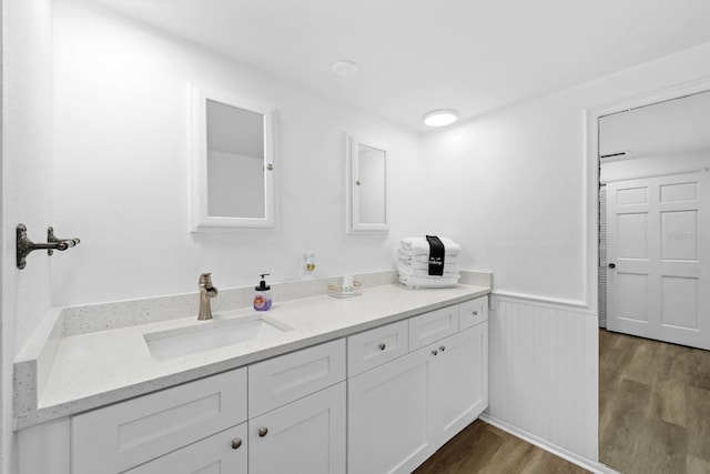 bathroom with wainscoting, wood finished floors, and vanity