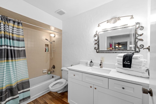 full bathroom with visible vents, a textured wall, wood finished floors, shower / bathtub combination with curtain, and vanity