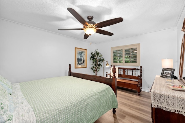 bedroom with light wood-style flooring, ornamental molding, and a textured ceiling