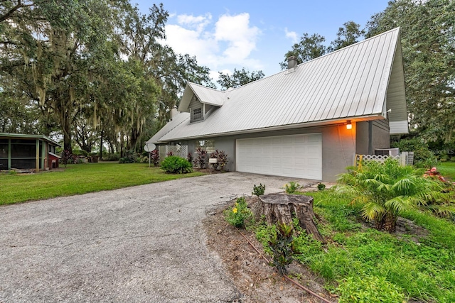 view of front facade with a garage, metal roof, a front lawn, and aphalt driveway