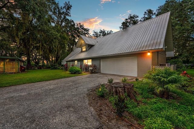 view of front of property with a garage, concrete driveway, metal roof, a yard, and stucco siding