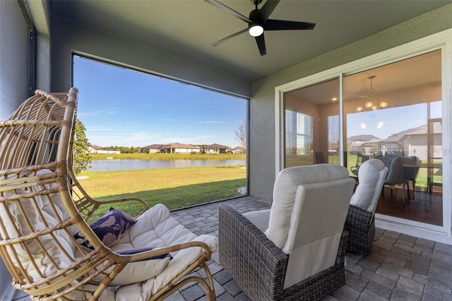 sunroom / solarium with a water view, a healthy amount of sunlight, and ceiling fan with notable chandelier