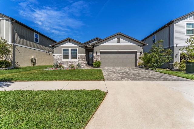 view of front of property featuring decorative driveway, stucco siding, a front yard, a garage, and stone siding