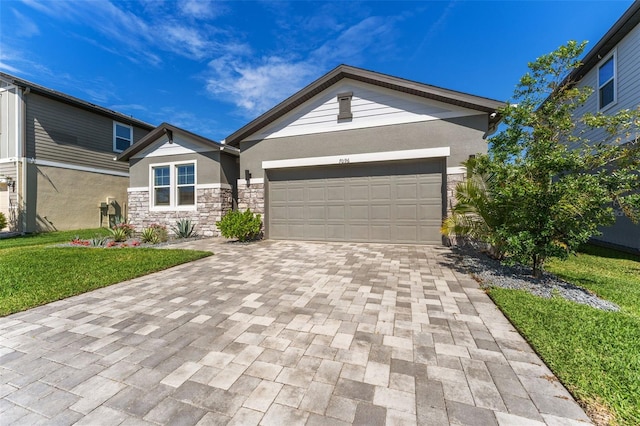 view of front of house featuring stone siding, an attached garage, decorative driveway, a front lawn, and stucco siding