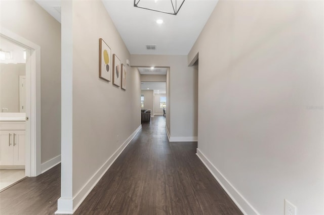 hall with dark wood-style floors, visible vents, and baseboards