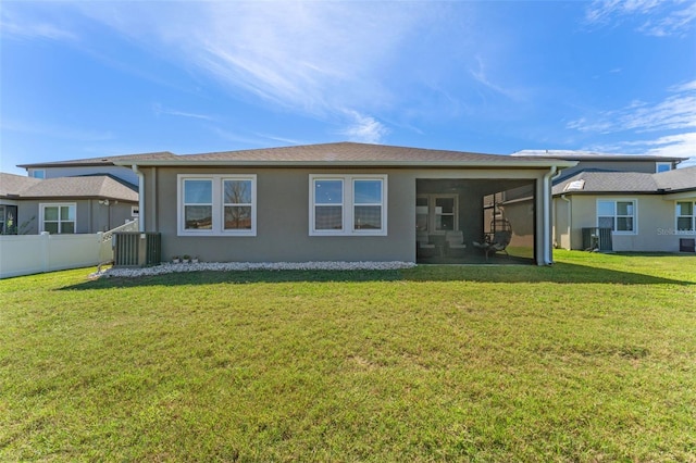 back of property with central air condition unit, fence, a sunroom, a lawn, and stucco siding