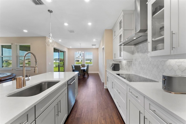 kitchen with a sink, visible vents, dishwasher, wall chimney exhaust hood, and pendant lighting