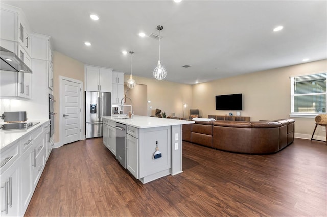 kitchen featuring a sink, open floor plan, light countertops, appliances with stainless steel finishes, and dark wood finished floors