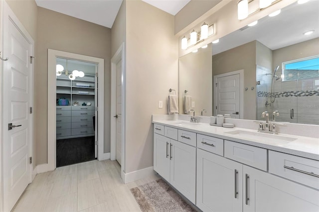 bathroom featuring double vanity, a stall shower, a sink, and a walk in closet