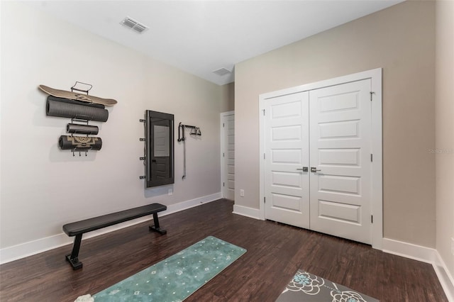 exercise room with wood finished floors, visible vents, and baseboards