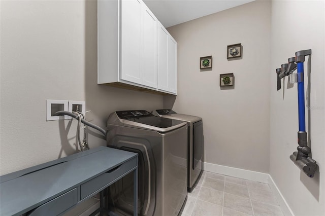 washroom featuring cabinet space, independent washer and dryer, baseboards, and light tile patterned flooring