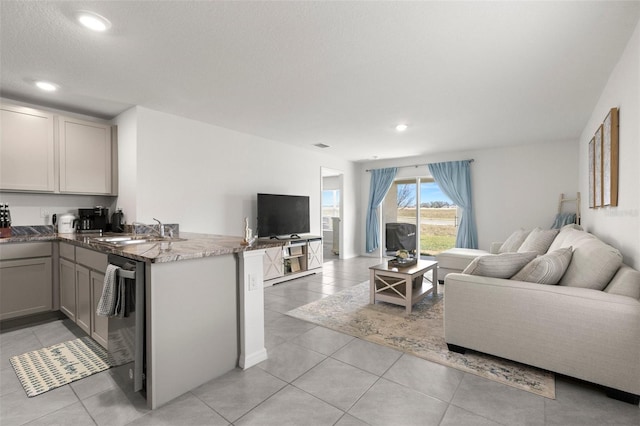 kitchen featuring recessed lighting, open floor plan, a sink, a peninsula, and dishwashing machine