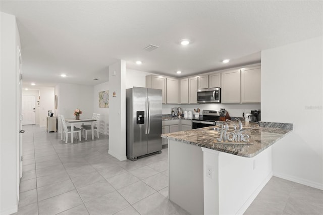 kitchen featuring stone counters, gray cabinets, visible vents, appliances with stainless steel finishes, and a peninsula