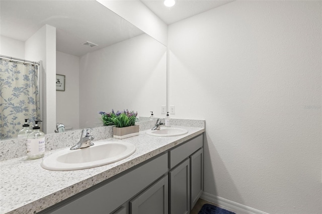 bathroom featuring double vanity, baseboards, visible vents, and a sink