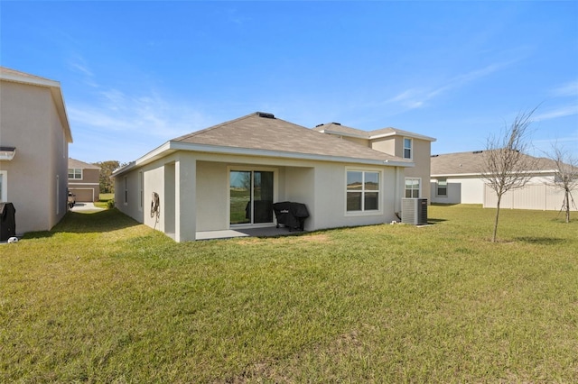 back of property with central AC unit, a lawn, and stucco siding