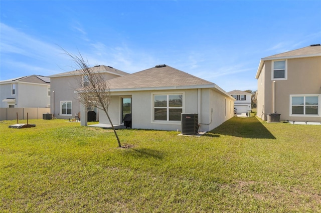 rear view of property with cooling unit, fence, a lawn, and stucco siding