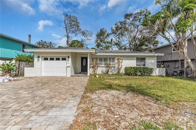 view of front facade featuring a garage, fence, decorative driveway, stucco siding, and a front lawn