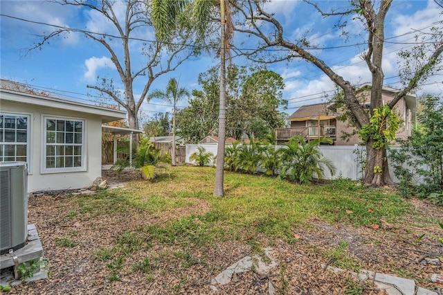 view of yard with central AC and fence