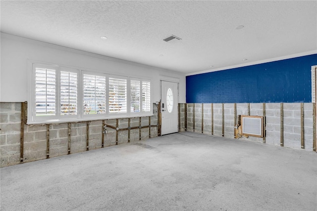 carpeted empty room with visible vents, crown molding, and a textured ceiling