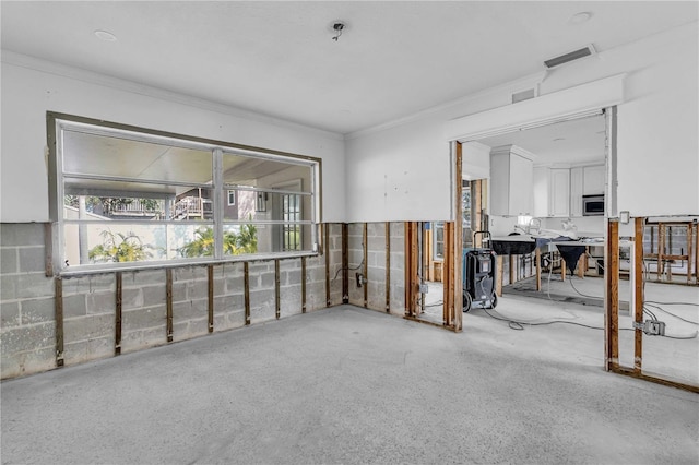 unfurnished room with concrete block wall, visible vents, and crown molding