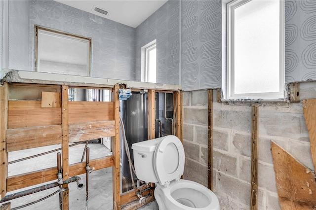 bathroom with a healthy amount of sunlight, visible vents, toilet, and wallpapered walls