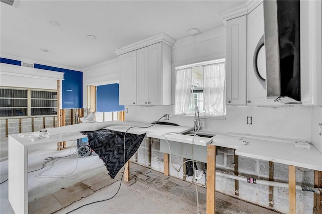 kitchen with stainless steel microwave, a sink, white cabinetry, and crown molding