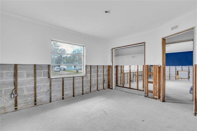 unfurnished room featuring visible vents and concrete block wall