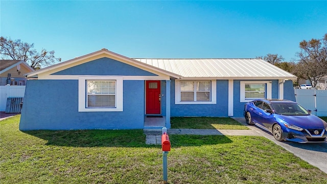 view of front of house with a front yard, metal roof, and stucco siding