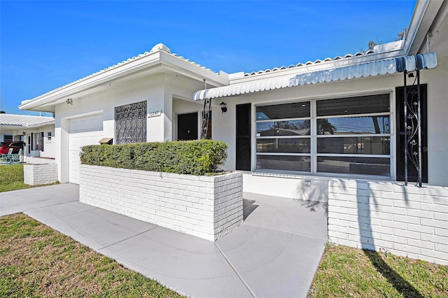 exterior space featuring a garage, concrete driveway, and stucco siding