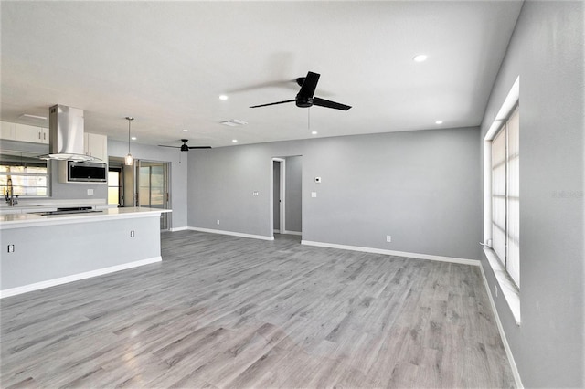 unfurnished living room with ceiling fan, recessed lighting, light wood-style flooring, and baseboards