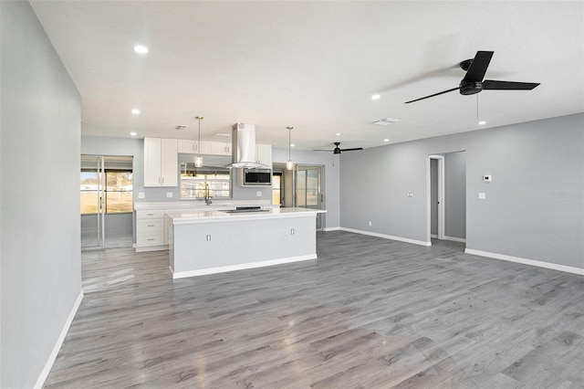 kitchen featuring white cabinets, a kitchen island, appliances with stainless steel finishes, open floor plan, and island exhaust hood