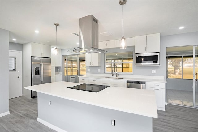 kitchen featuring island exhaust hood, stainless steel appliances, white cabinets, a sink, and a kitchen island