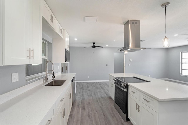 kitchen with island exhaust hood, stainless steel appliances, open floor plan, white cabinets, and a sink