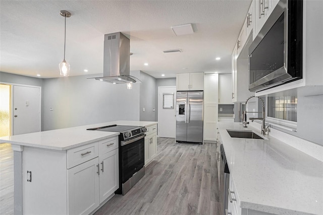 kitchen with island exhaust hood, stainless steel appliances, white cabinets, a sink, and a kitchen island