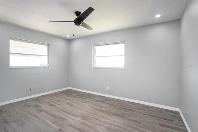 spare room with recessed lighting, plenty of natural light, wood finished floors, and baseboards