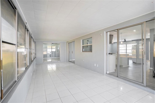 unfurnished sunroom featuring a ceiling fan