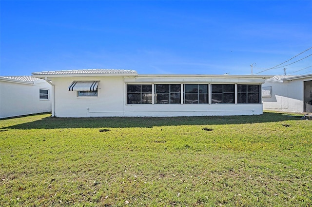 rear view of property featuring a lawn and a sunroom