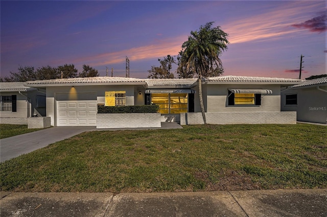 single story home with driveway, an attached garage, a front lawn, and stucco siding