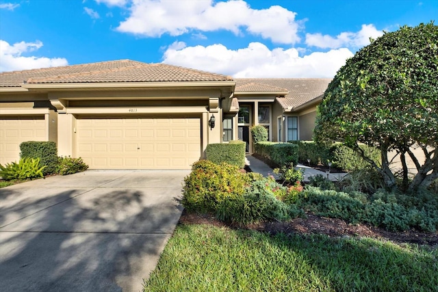 view of front of house with driveway, a tile roof, a garage, and stucco siding