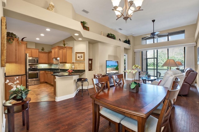 dining room featuring ceiling fan with notable chandelier, visible vents, baseboards, and wood finished floors