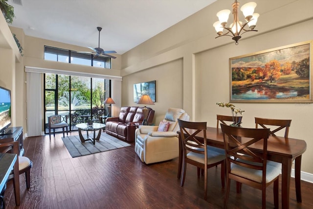 living area featuring ceiling fan with notable chandelier, dark wood-style flooring, and baseboards