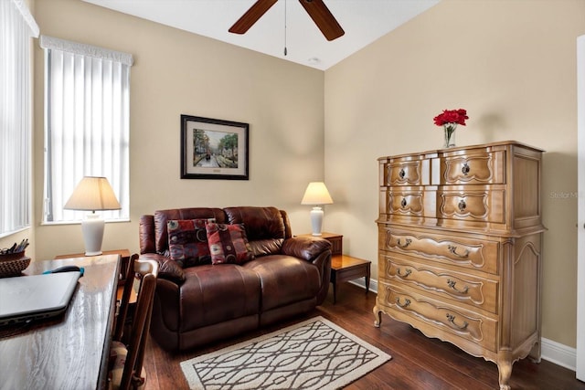 living area with baseboards, dark wood finished floors, and a ceiling fan