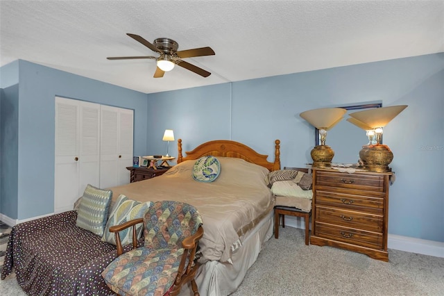 carpeted bedroom with a textured ceiling, ceiling fan, a closet, and baseboards