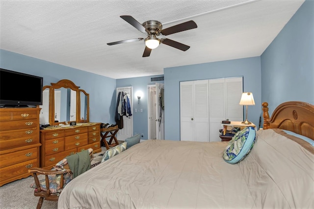 bedroom featuring multiple closets, carpet floors, a textured ceiling, and a ceiling fan