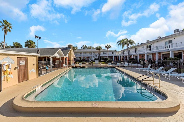 community pool featuring a residential view, fence, and a patio