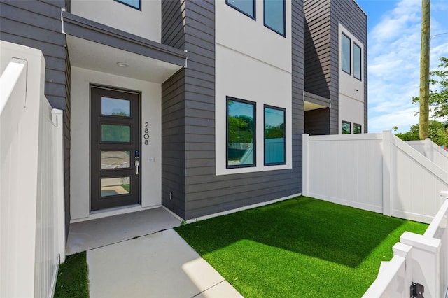 property entrance with a lawn and fence