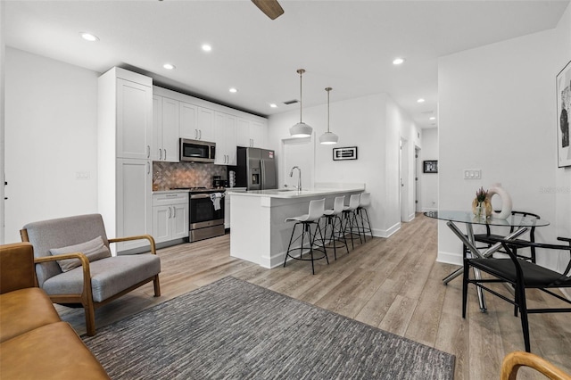 living area featuring light wood-type flooring, visible vents, baseboards, and recessed lighting